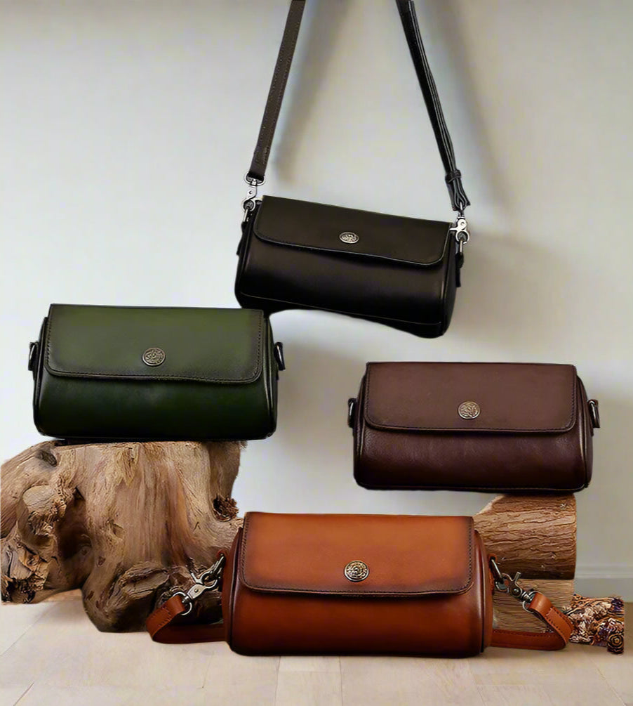 Four leather handbags in green, brown, and black on a white background with wooden logs.
