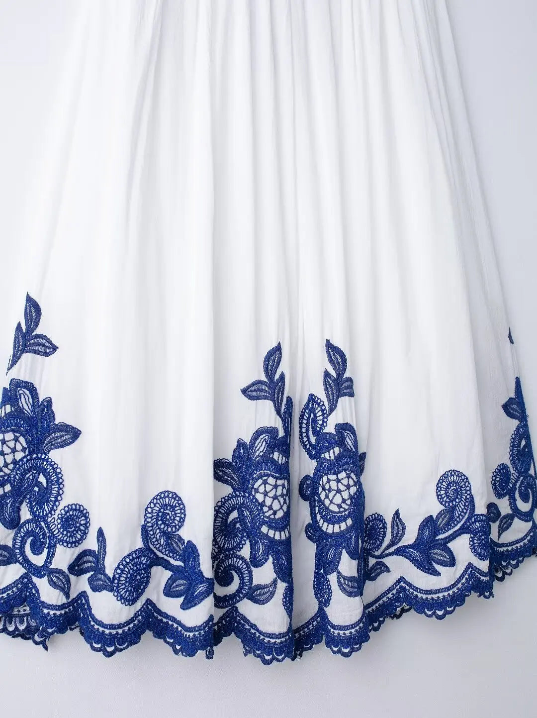 White fabric with blue lace detailing on a white background