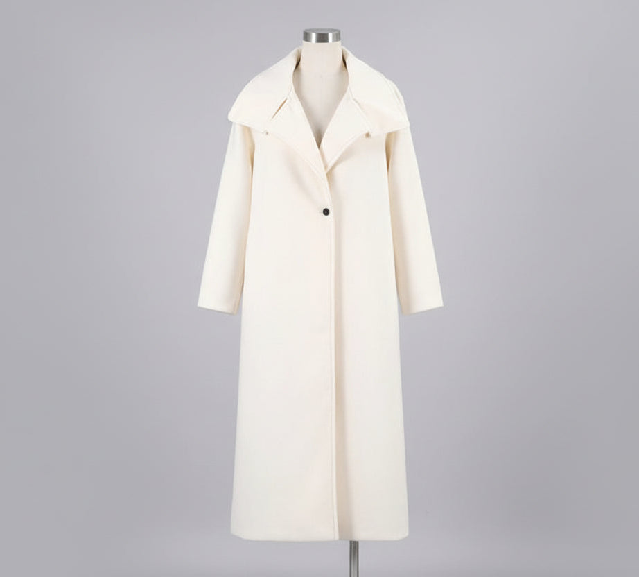 White coat on a hanger against a white wall with a plant and framed picture in the background.