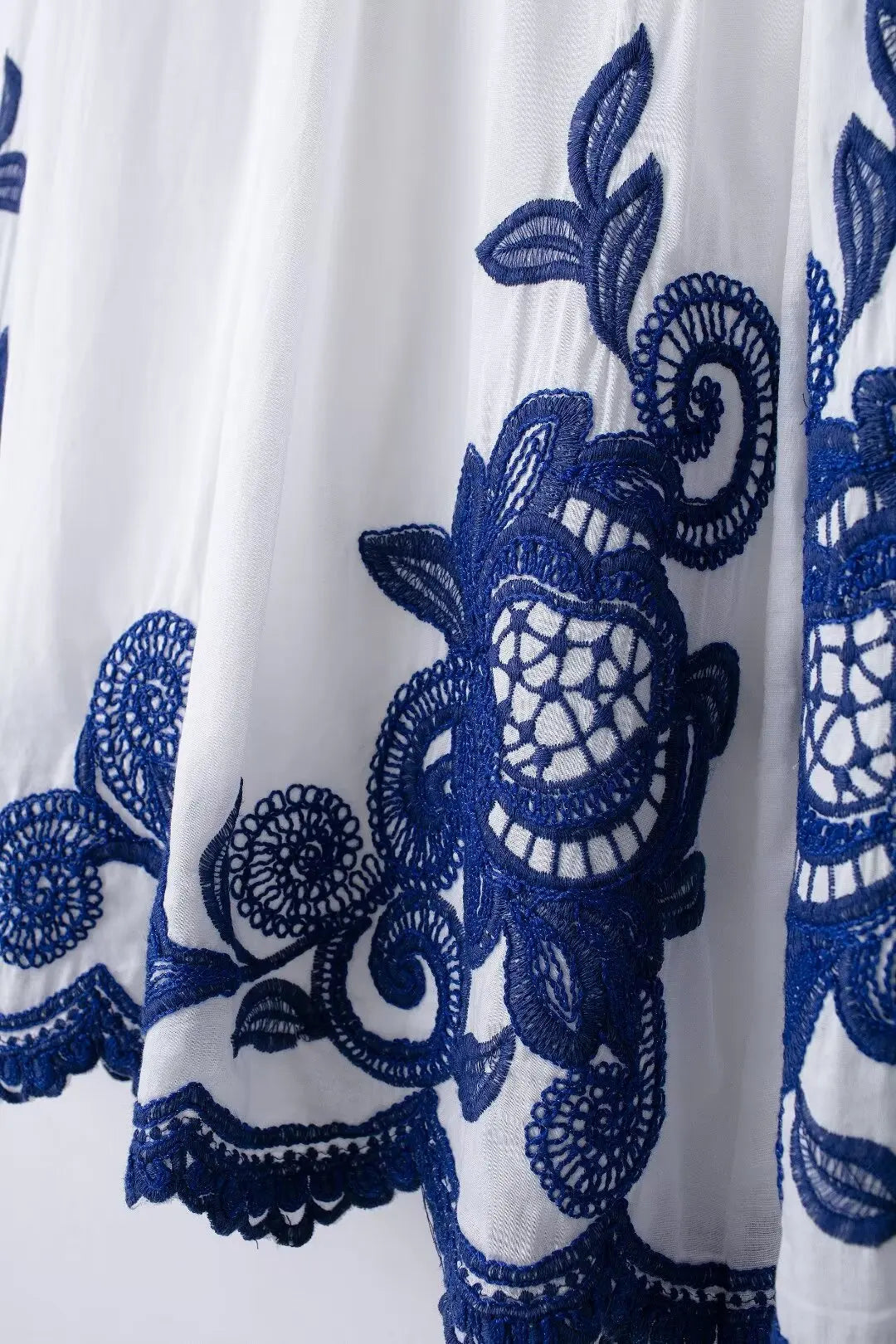 White fabric with intricate blue floral embroidery