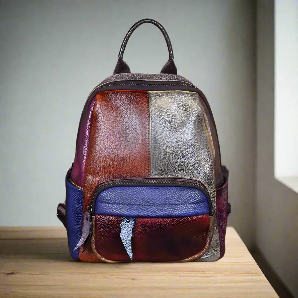 Multicolored leather backpack on a wooden table with a white wall background