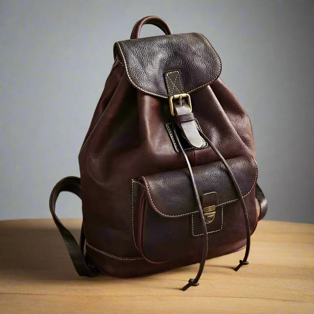 Brown leather backpack on a wooden surface with a neutral background