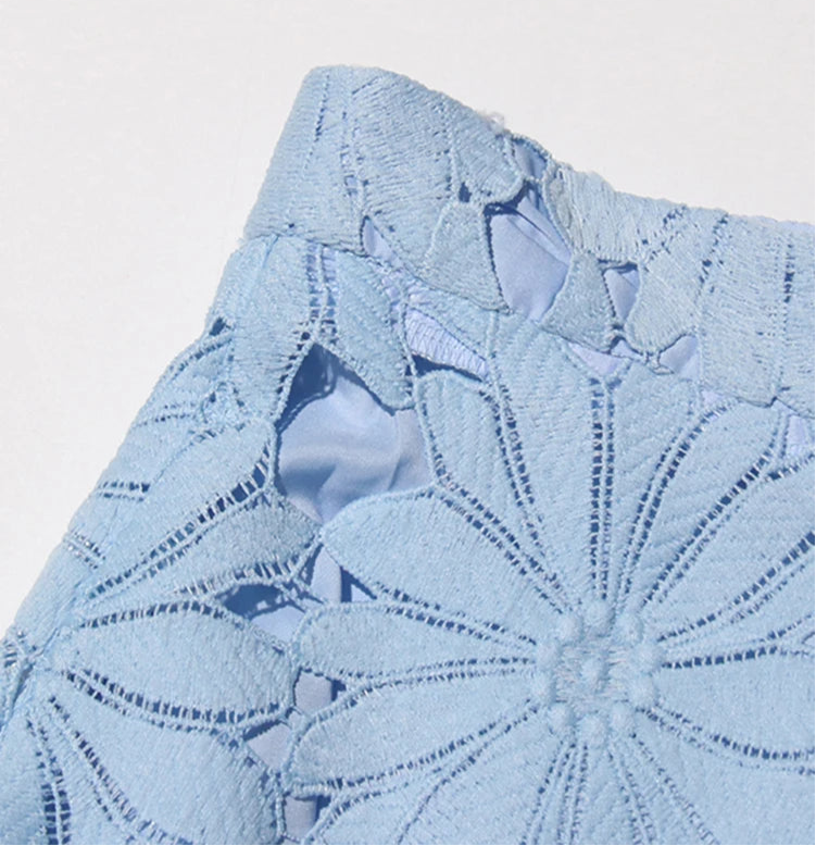 Close-up of a blue lace garment with intricate patterns on a light gray background