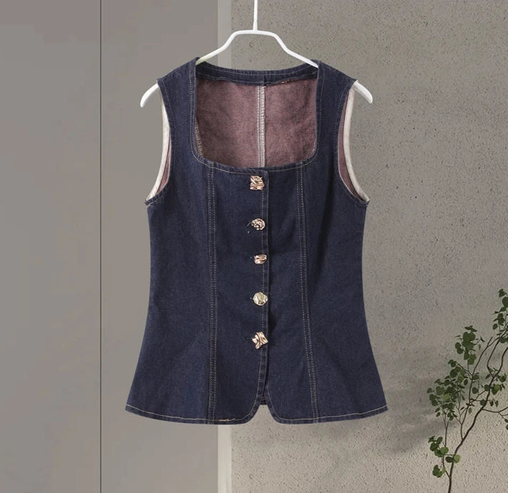 Denim vest on a hanger against a plain background