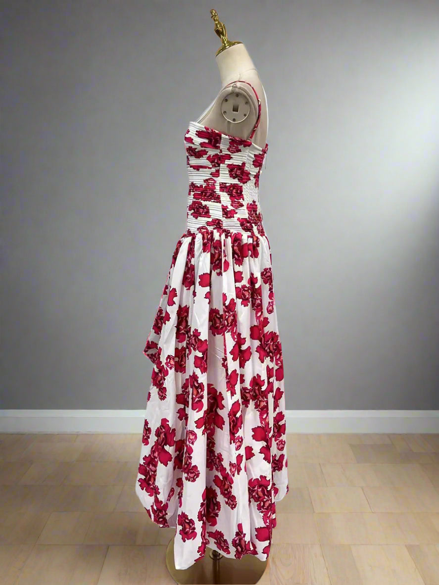 White dress with red floral pattern on a mannequin against a plain background