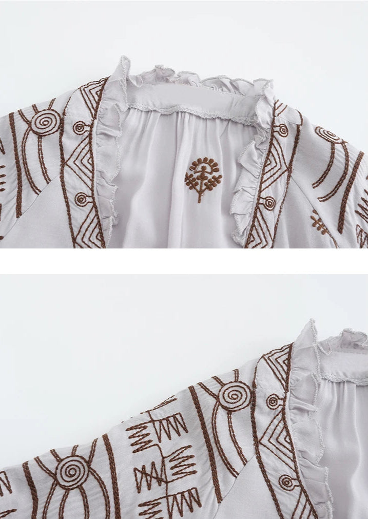 White dress with brown patterns and embroidery on a white background