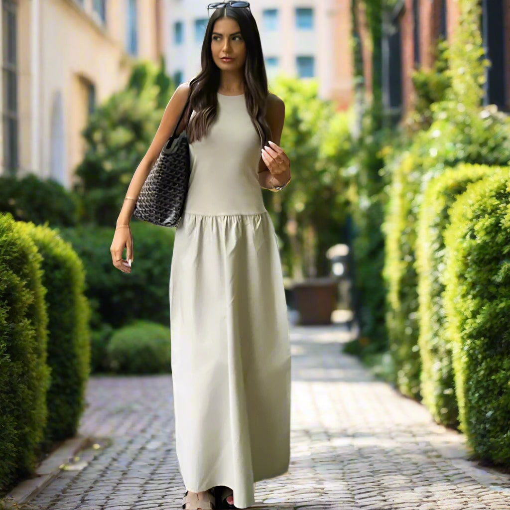 Woman in a long light-colored dress against backyard garden