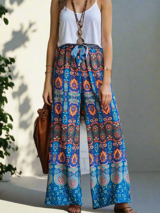 Person wearing a colorful patterned skirt with a white top and brown bag outdoors.