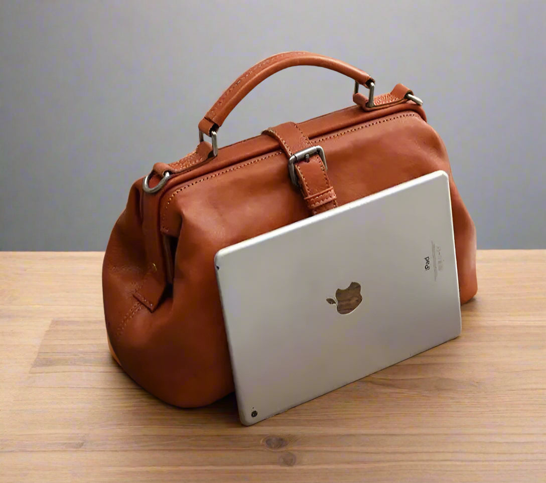 Brown leather handbag with a laptop on a wooden surface