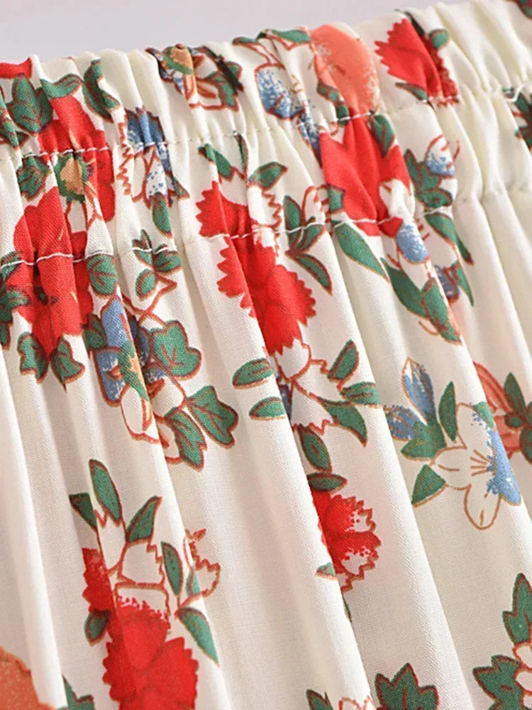 Floral patterned fabric with red flowers and green leaves on a white background