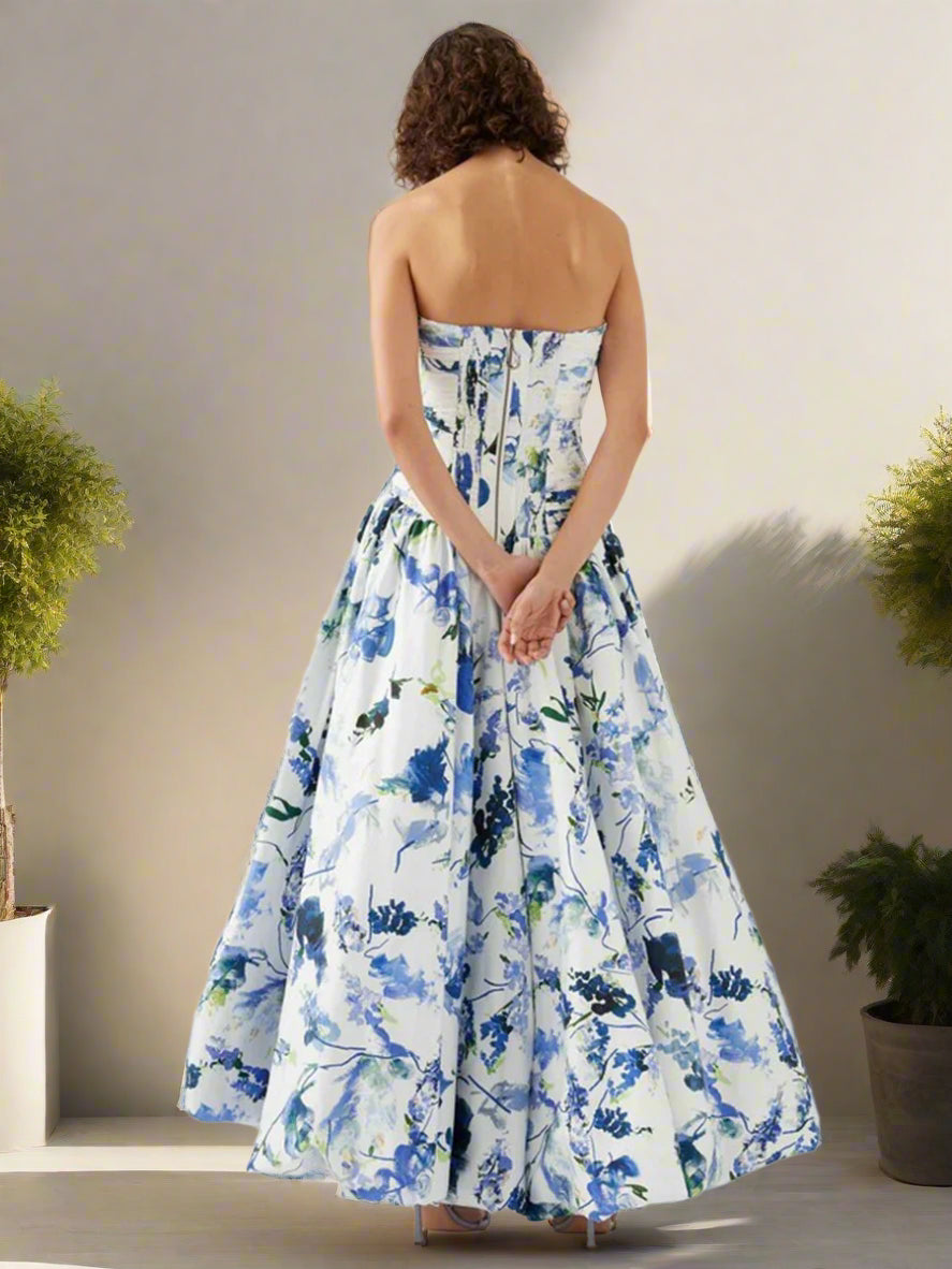 Woman wearing a strapless floral dress with blue and green flowers on a backyard garden, sunny day