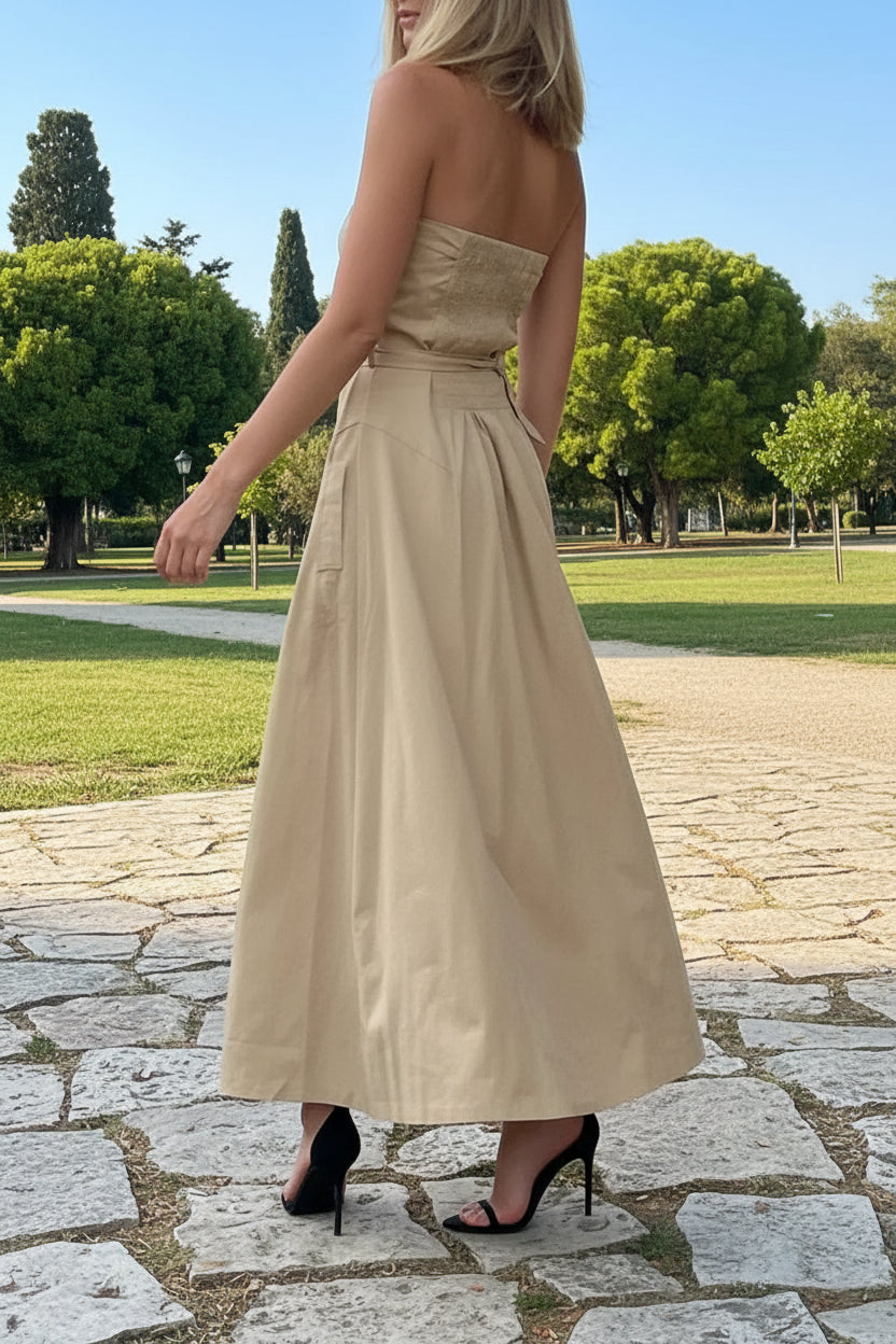 Woman in a beige strapless dress walking on an open park.