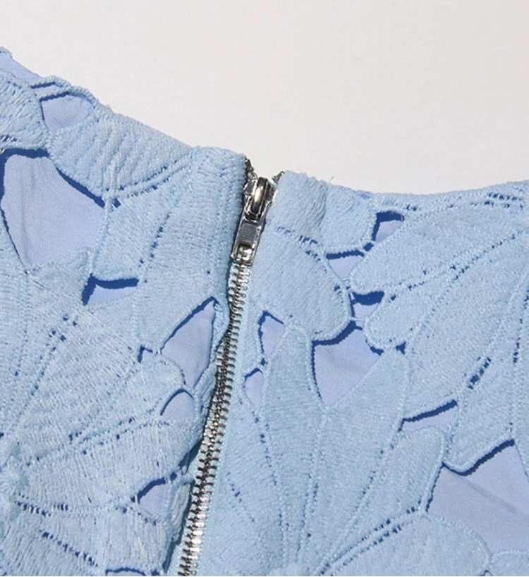 Close-up of a light blue jacket with leaf patterns and a zipper on a white background