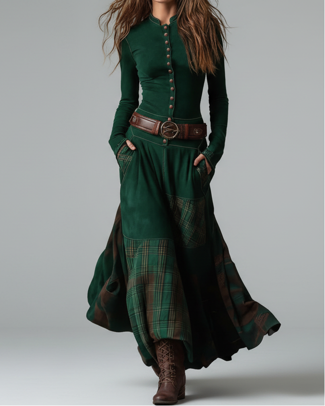 Woman wearing a long green dress with plaid pattern and brown belt against a gray background