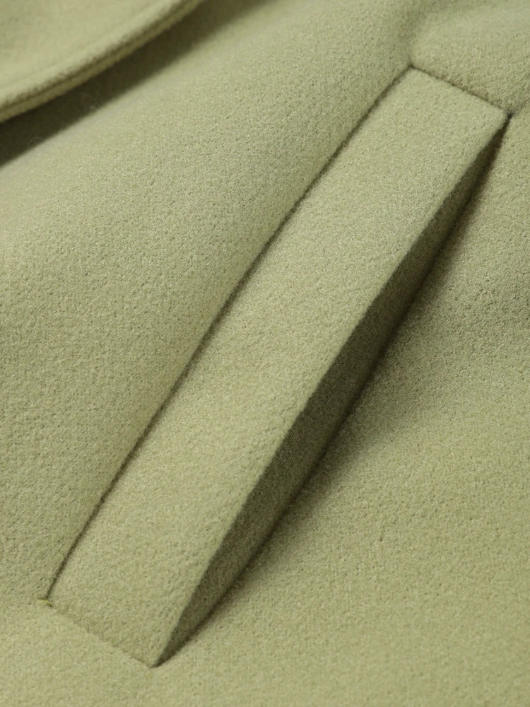 Close-up of a green coat with a lapel and button detail