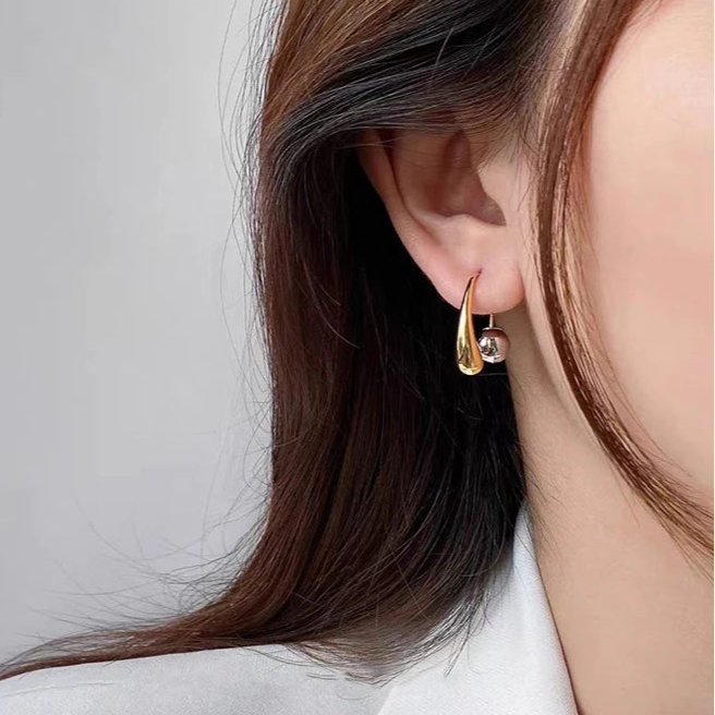Gold hoop earring worn by a person with a neutral background
