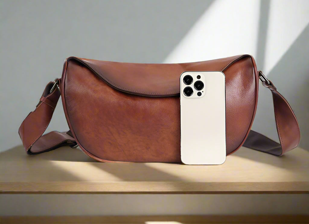 Brown leather bag  and an iPhone for scale on a white background