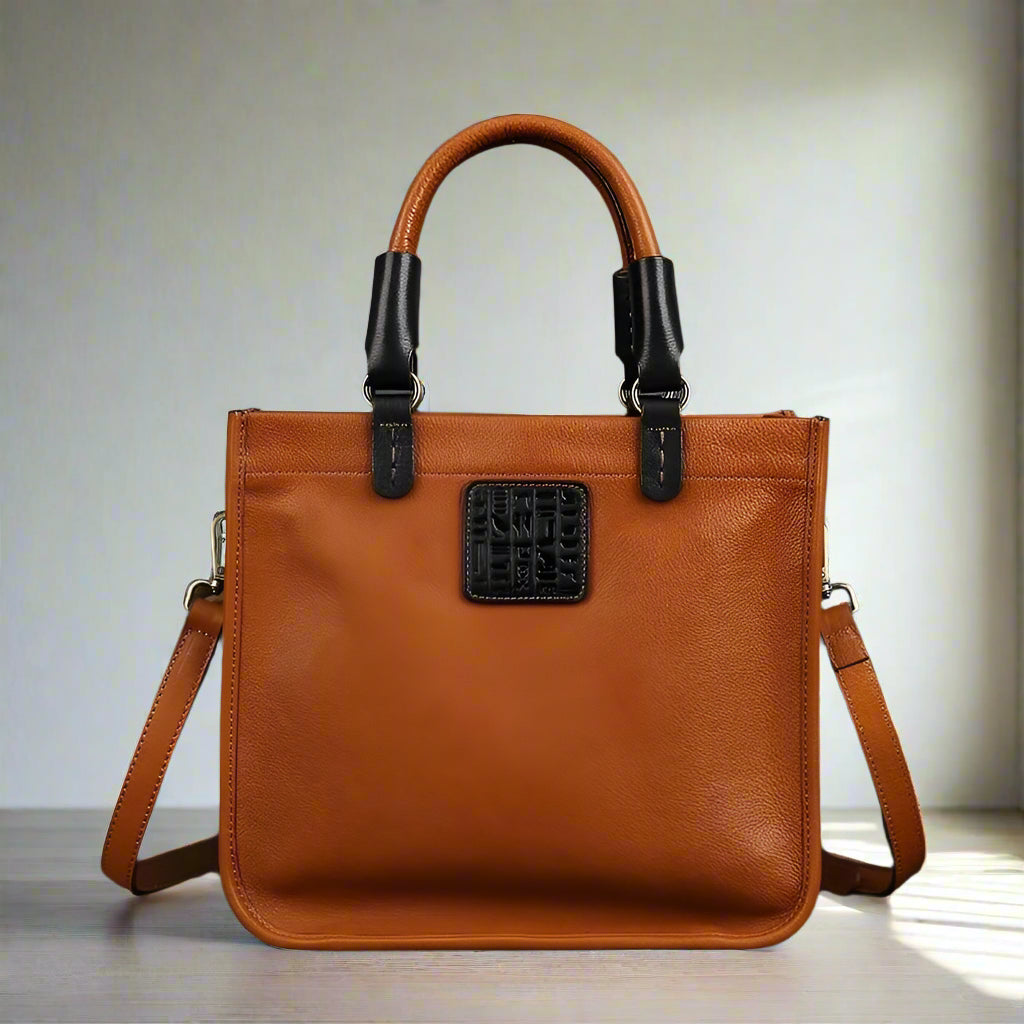 Brown leather handbag with black accents on a white background