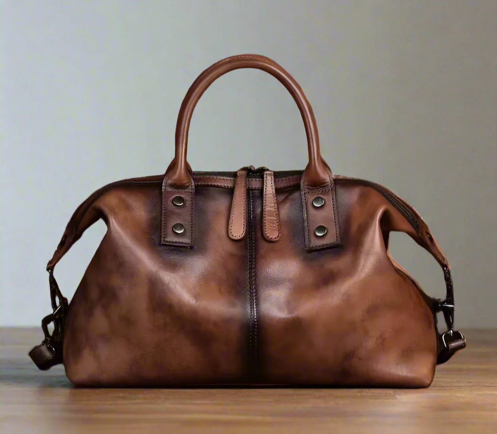 Brown leather handbag on a wooden surface with a white background
