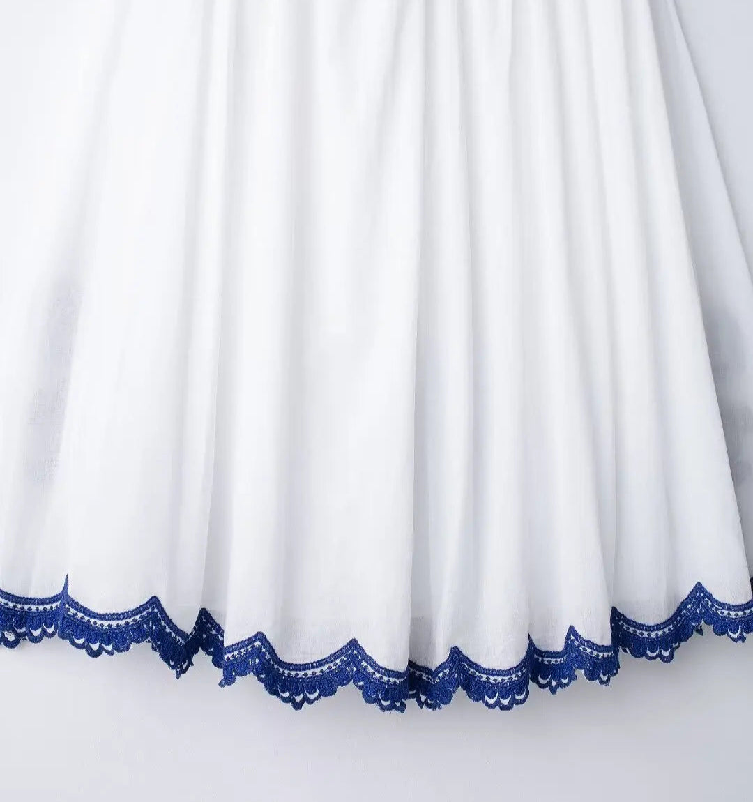 White fabric with blue lace trim on a white background