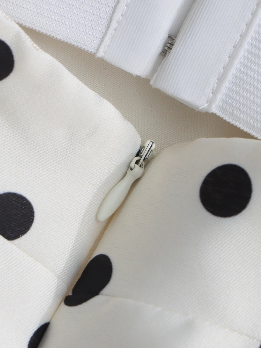 Close-up of a white pouch with black polka dots and an off-white zipper.
