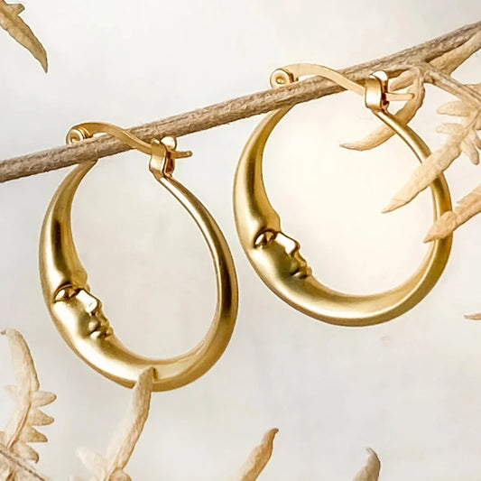 Gold hoop earrings on a branch with leaves