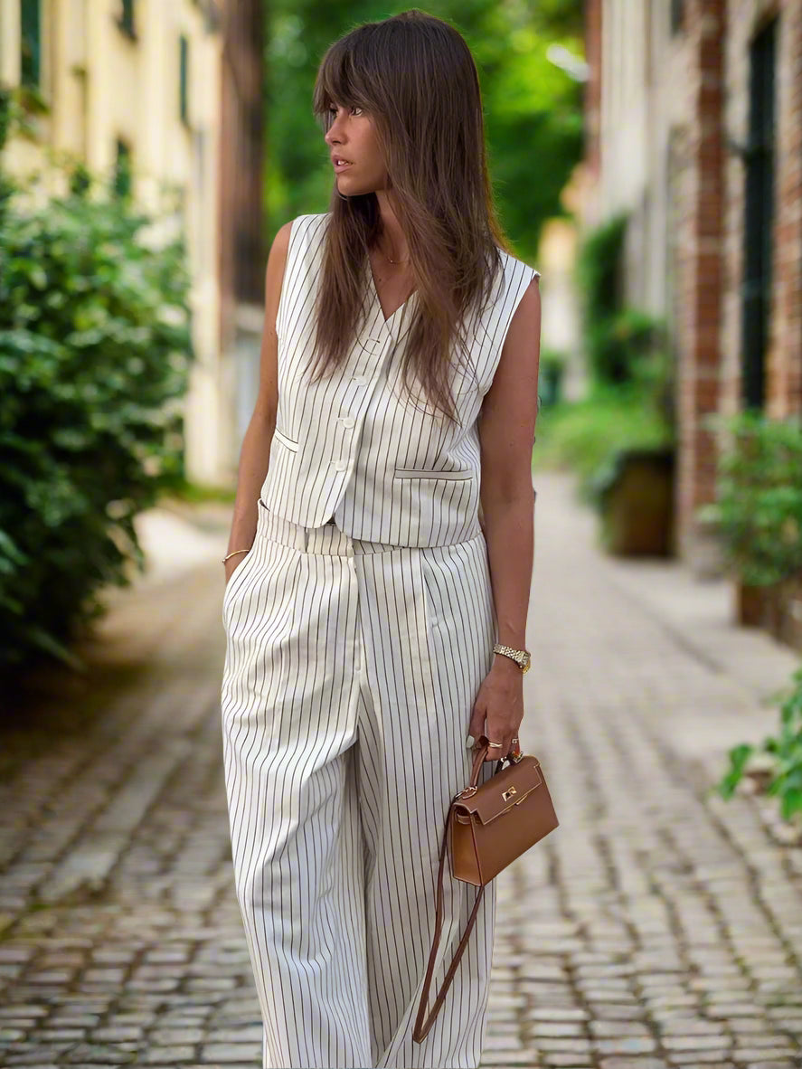 Woman in a striped outfit holding a brown handbag against a backyard garden, sunny