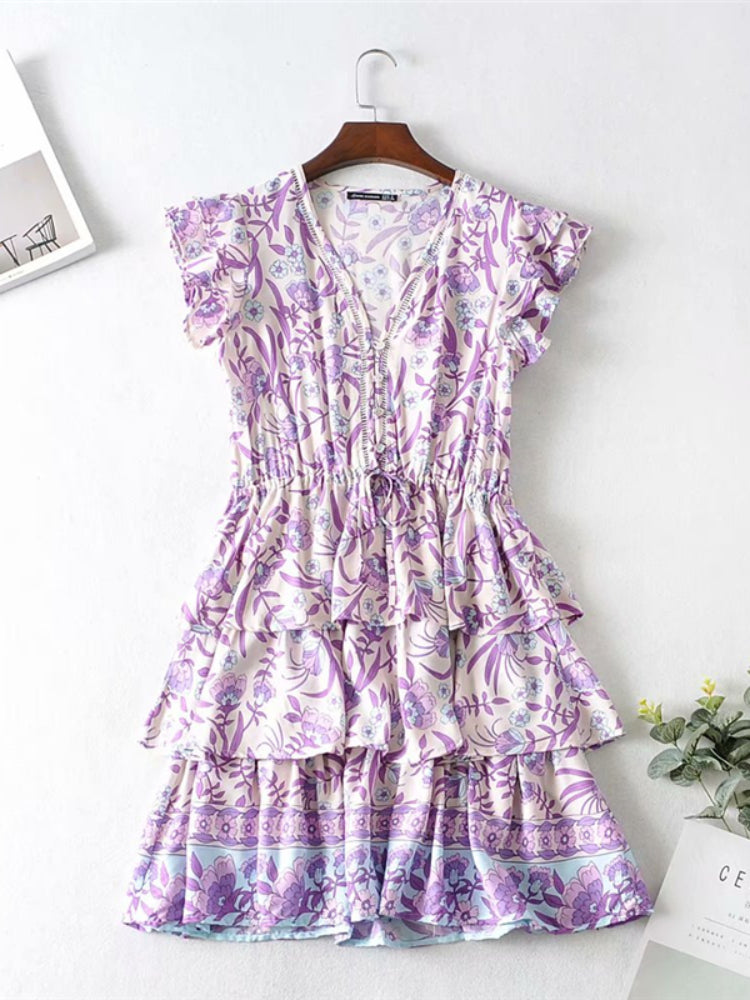 Purple floral dress on a hanger against a white background