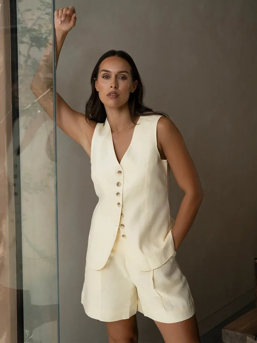 Woman wearing a cream-colored vest and shorts set against a neutral background