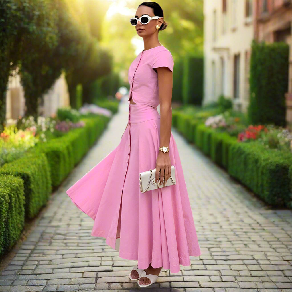 Woman in a pink outfit standing against a backyard garden, sunny