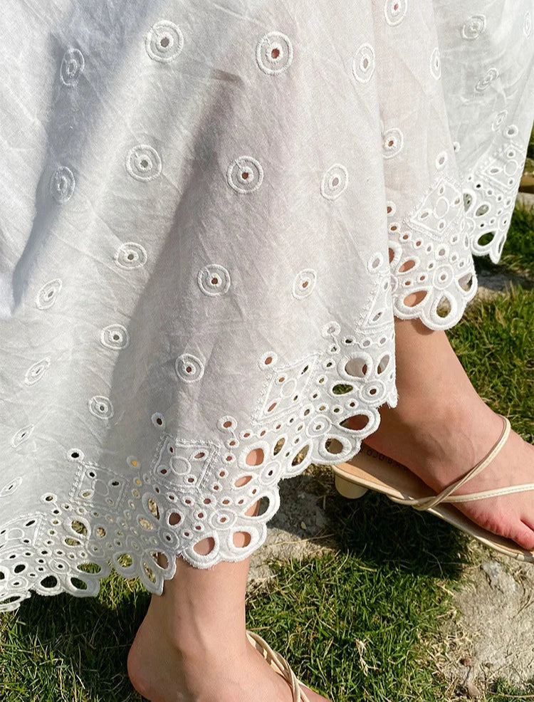 White skirt with intricate cut-out pattern worn by a person sitting on grass.