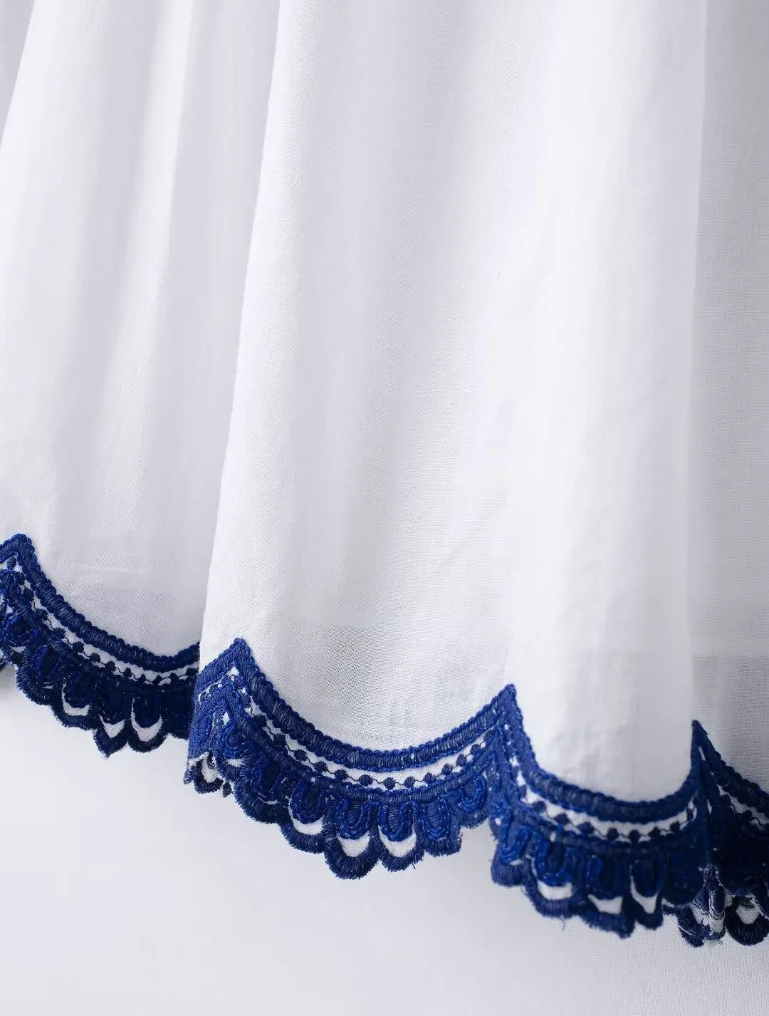 White fabric with blue lace trim on a white background