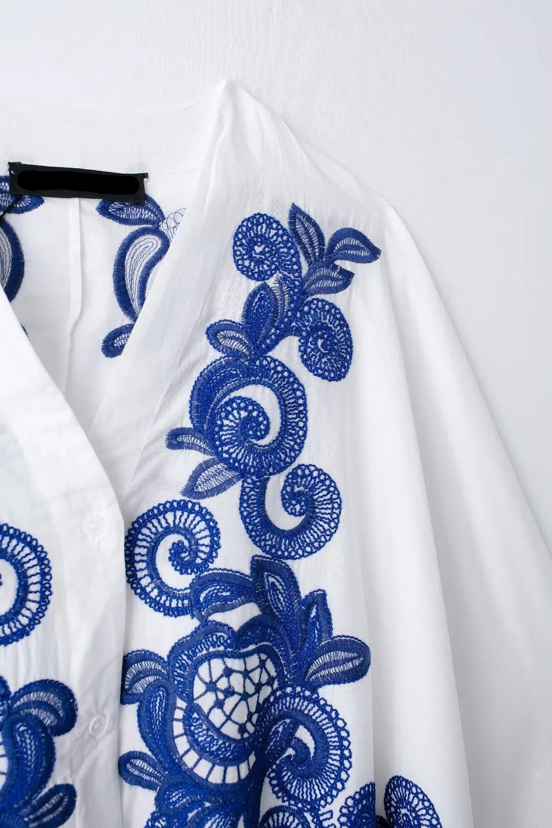 White fabric with blue floral embroidery and on a white background