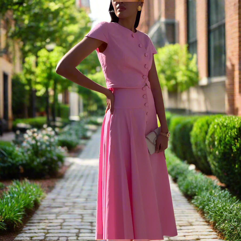 Woman wearing a pink dress standing against a backyard garden, sunny