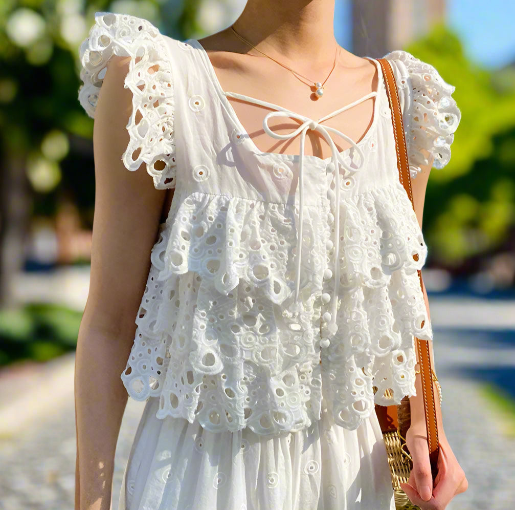 White lace top worn by a person with a blurred background