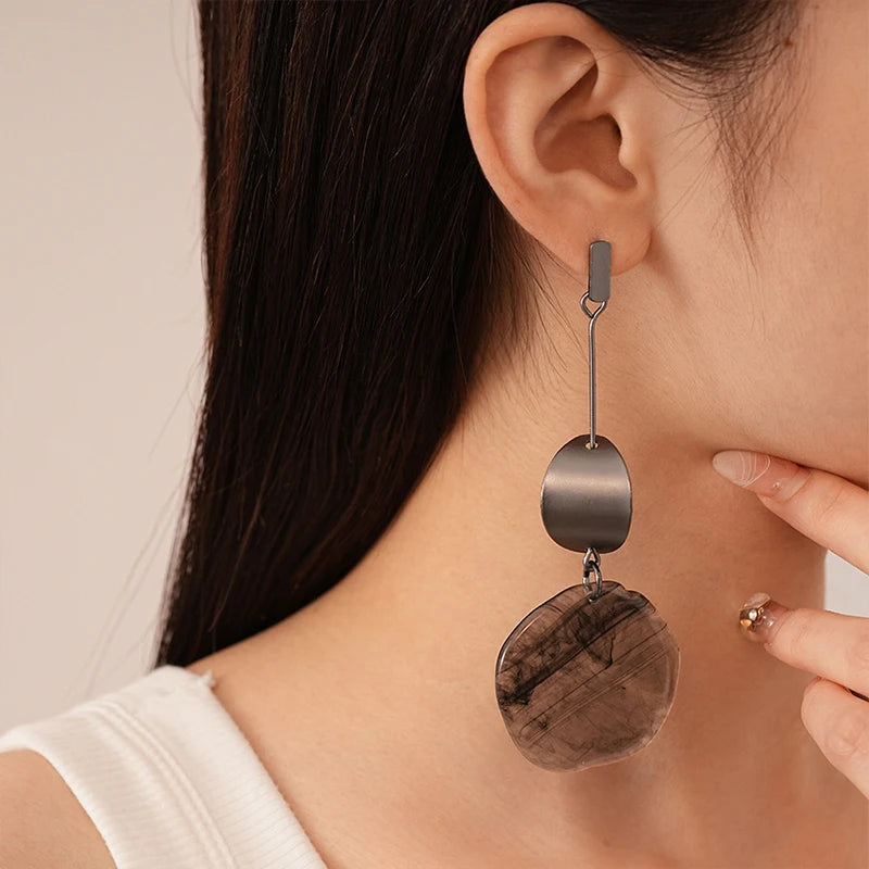 Close-up of a woman wearing a dangling earring with a neutral background