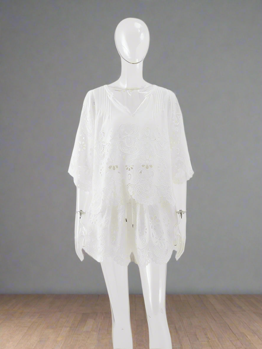 Mannequin wearing a sheer white dress with floral embellishments on a light gray background
