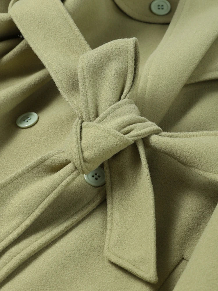 Close-up of a beige coat with a bow detail and button details.