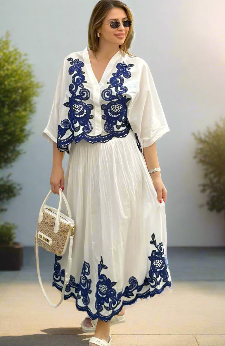Woman wearing a white skirt outfit set, with blue embroidery in a backyard