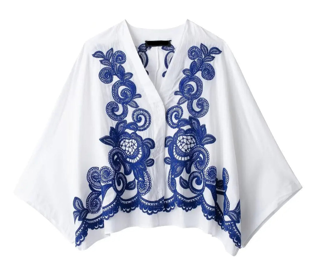 White garment with blue floral embroidery on a white background