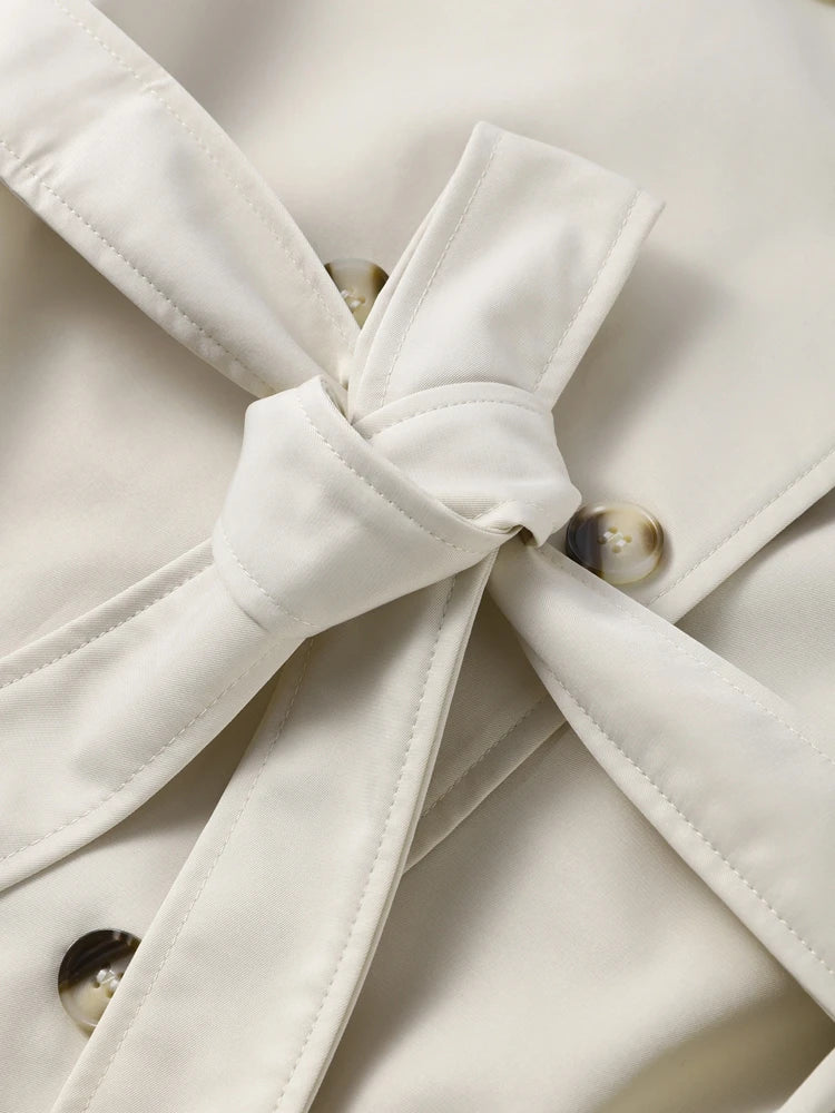 Close-up of a white coat with a bow detail