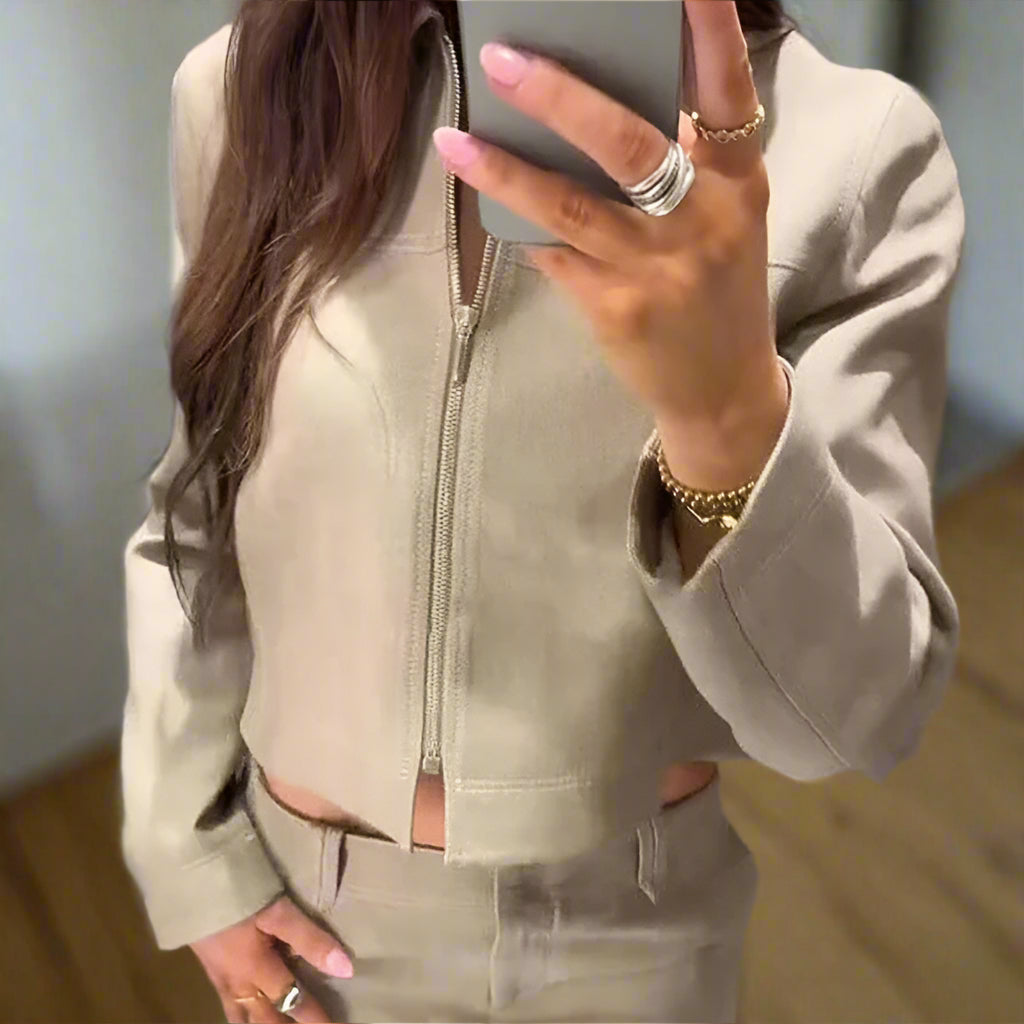 Person wearing a beige tracksuit taking a mirror selfie.
