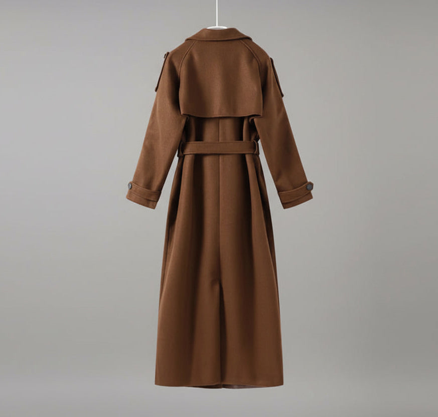 Brown trench coat on a hanger against a neutral wall 