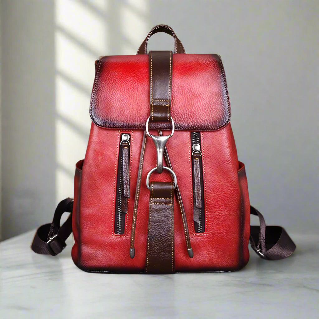 Red leather backpack with brown accents on a white table