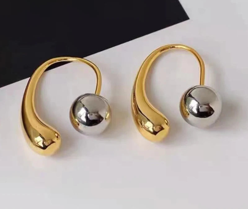 Gold and silver hoop earrings on a white surface