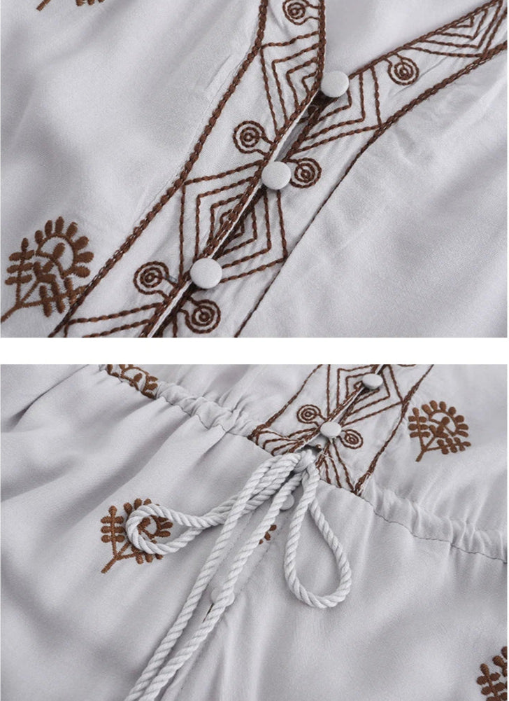 Close-up of a white garment with brown embroidery patterns.