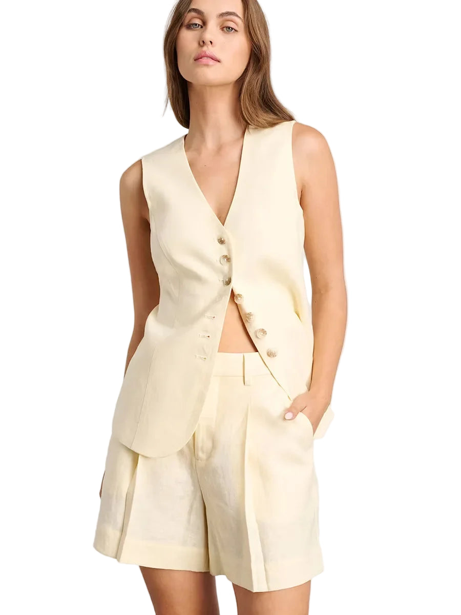 Woman wearing a light yellow vest and shorts set on a plain background