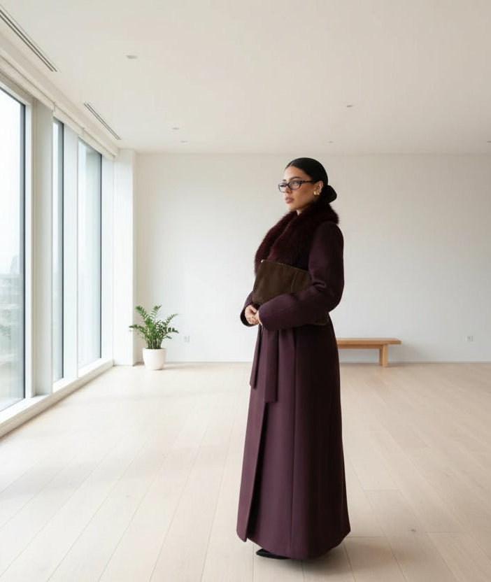 Woman in a long dark coat standing in an empty living room