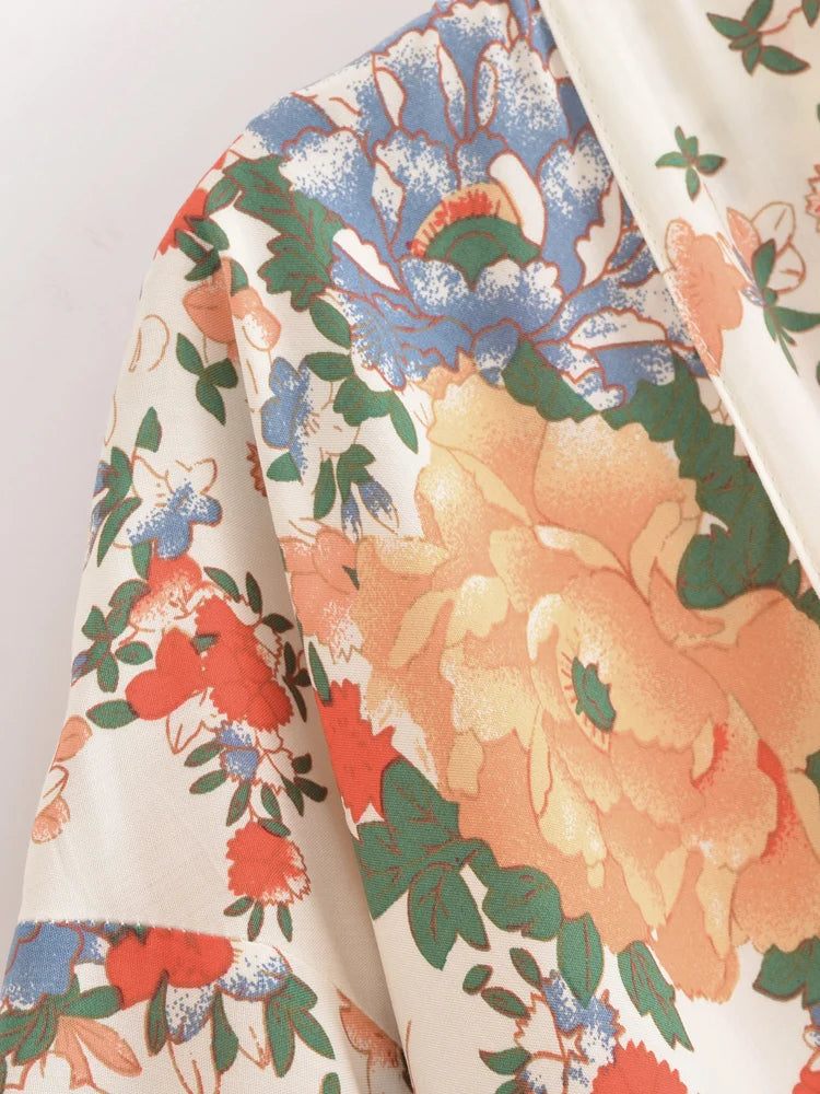 Close-up of a floral fabric with orange, blue, and green colors on a white background