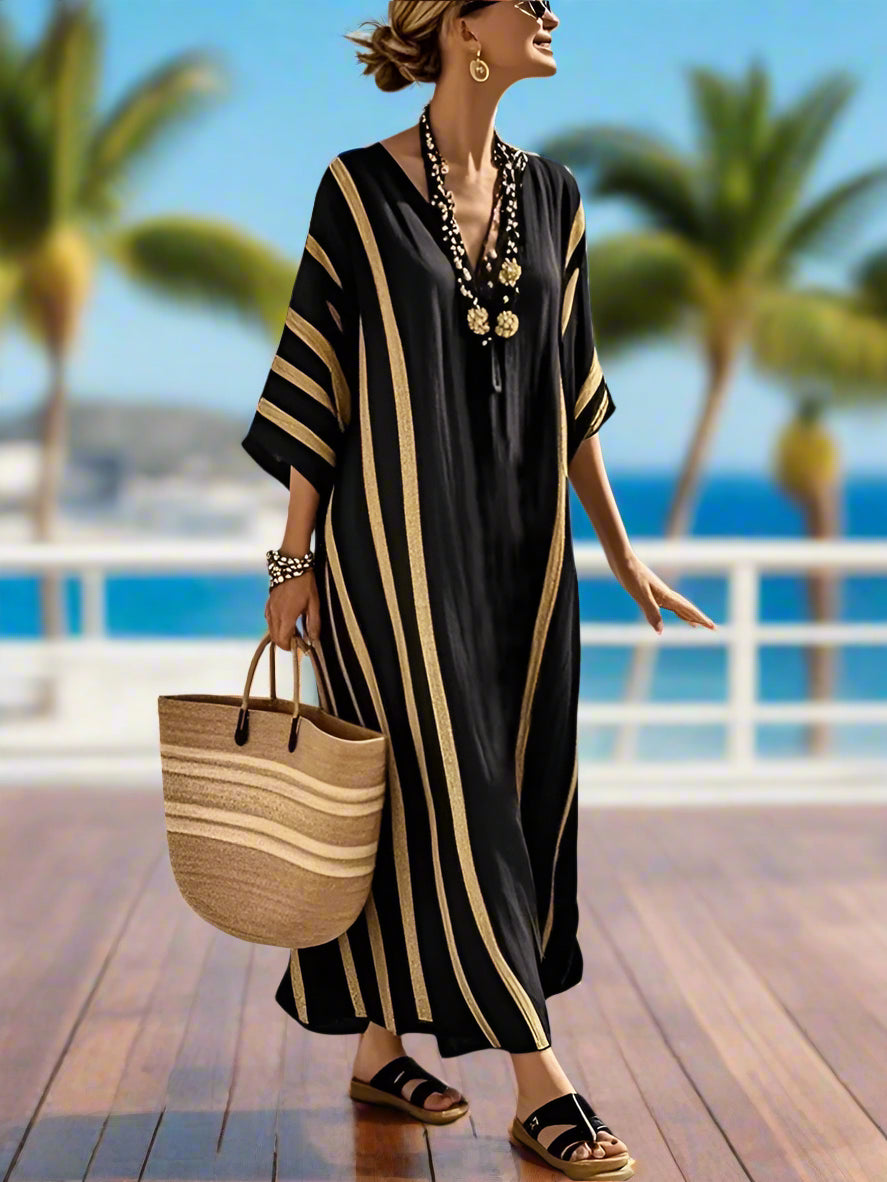 Woman in a black and gold dress with a straw bag standing on a wooden deck overlooking the ocean and palm trees
